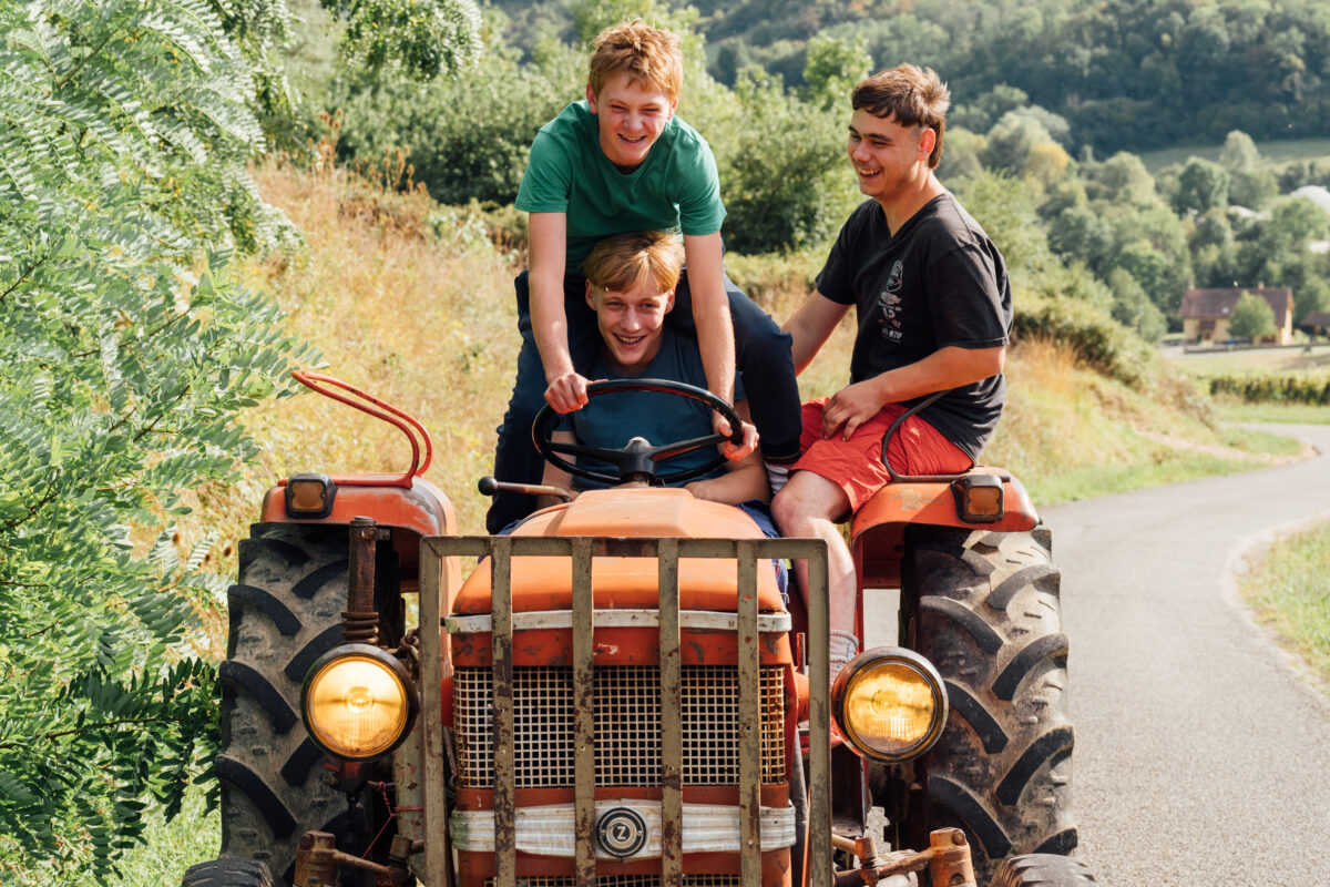 3 jeunes hommes, souriants, sur un tracteur